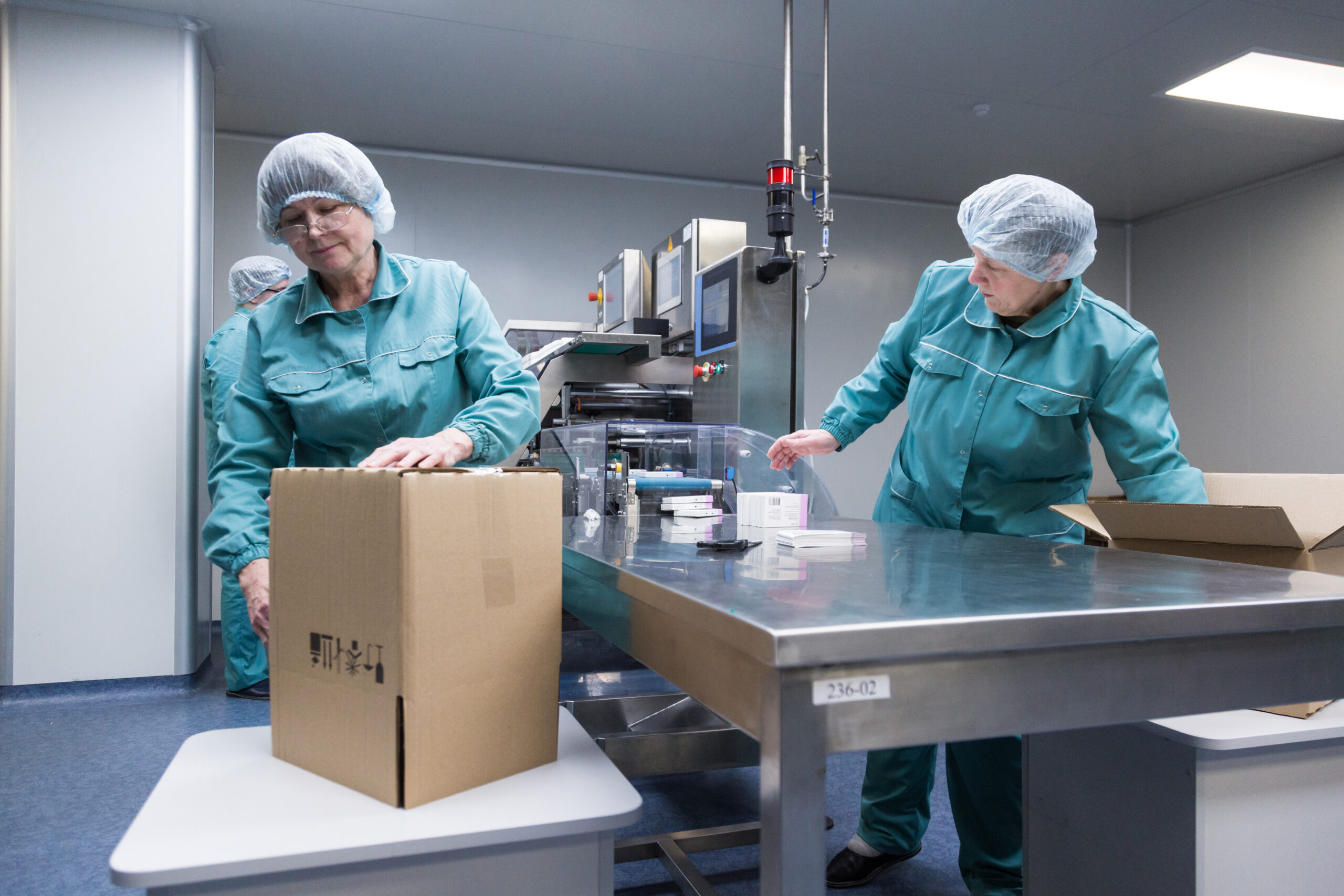 Pharmaceutical technicians work in sterile working conditions at pharmaceutical factory. Scientists wearing protective clothing